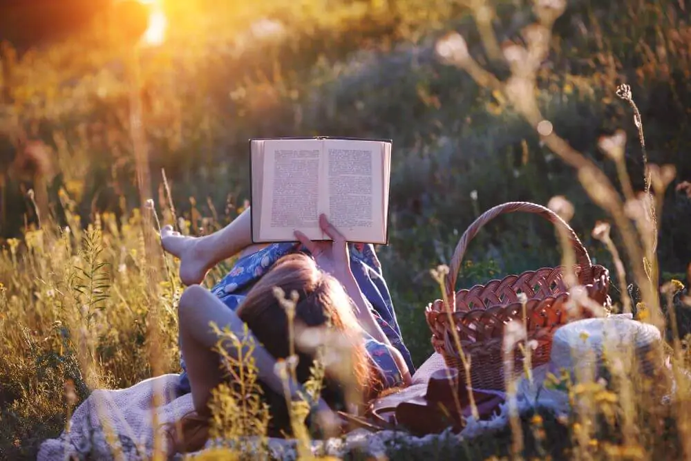 Female reading a book in a meadow field