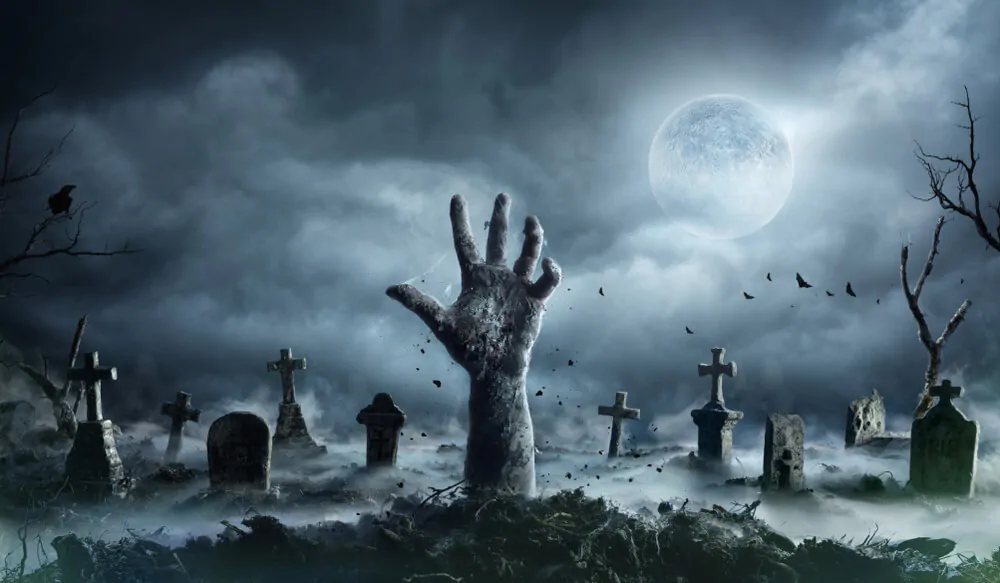 Zombie hand rising out of a graveyard in a spooky night