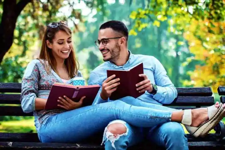 Hombre y Una mujer leyendo libros juntos en un banco